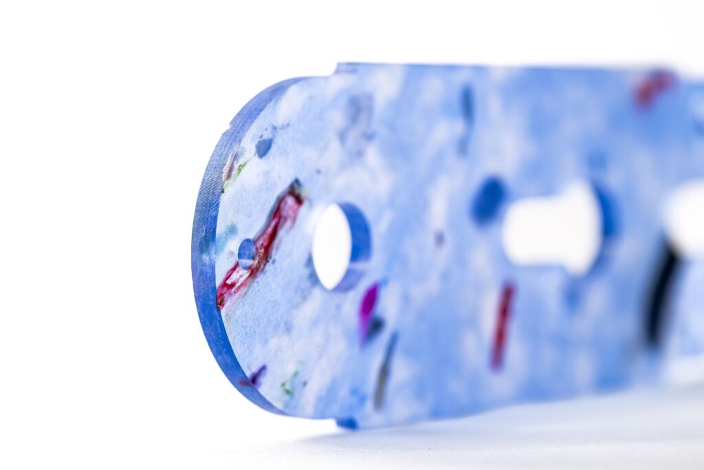 Nahaufnahme eines blauen kunststoffteils mit lochbohrungen und roter maserung