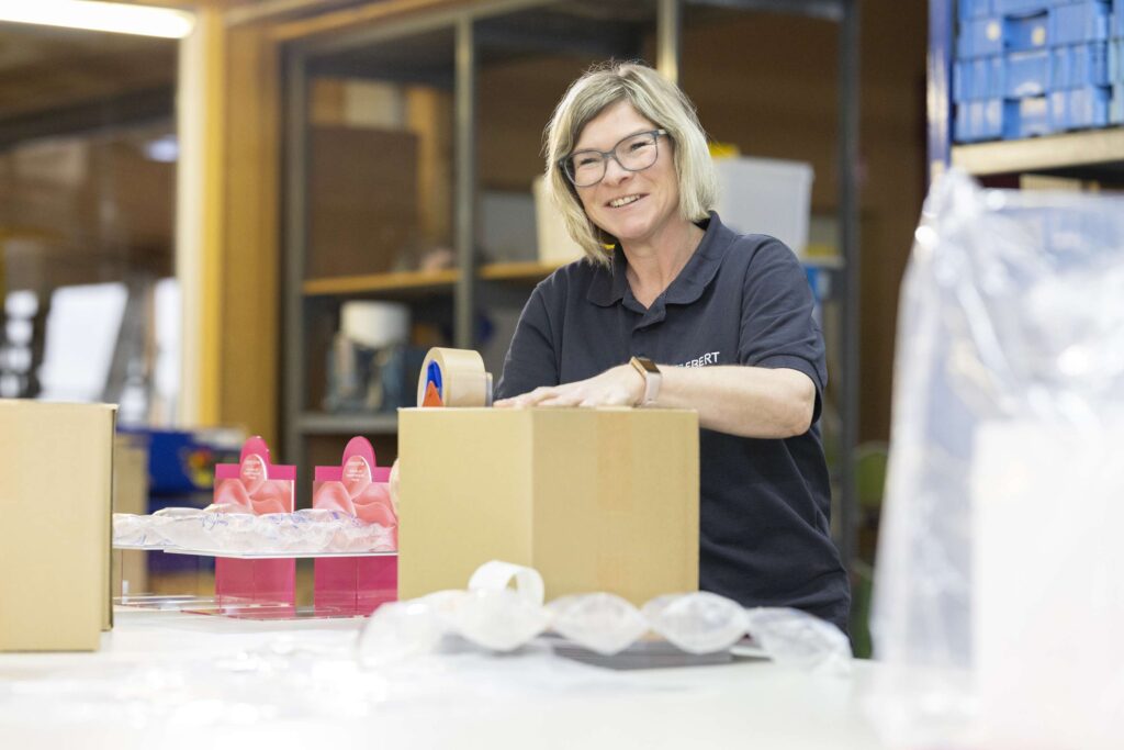 Mitarbeiterin von Ebert Kunststoffbearbeitung verpackt Produkte in einer Werkstatt.