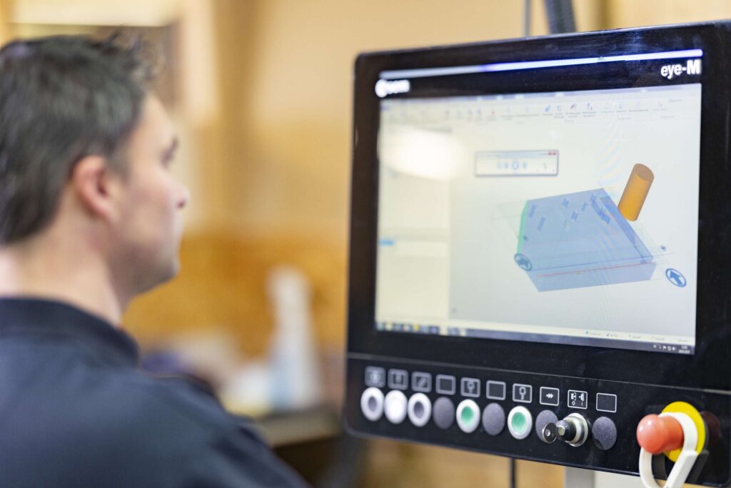 Mitarbeiter ueberwacht CNC-Maschine bei der Kunststoffbearbeitung bei Ebert Kunststoffbearbeitung.