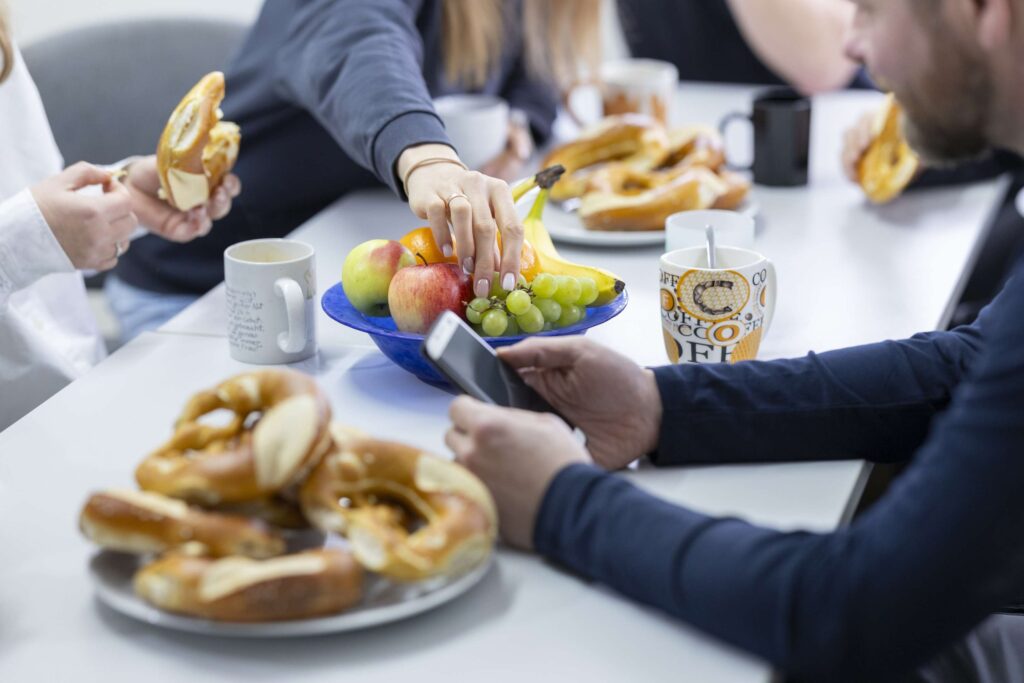 Mitarbeiter von Ebert Kunststoffbearbeitung im Pausenraum bei Brezeln und Obst.
