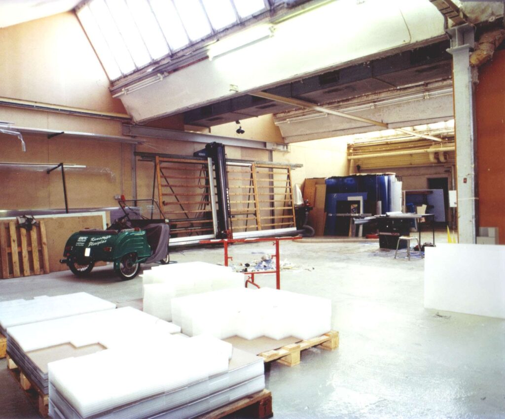 Innenansicht der fruehen Produktionshalle von Ebert Kunststoffbearbeitung mit Maschinen und Materialien.