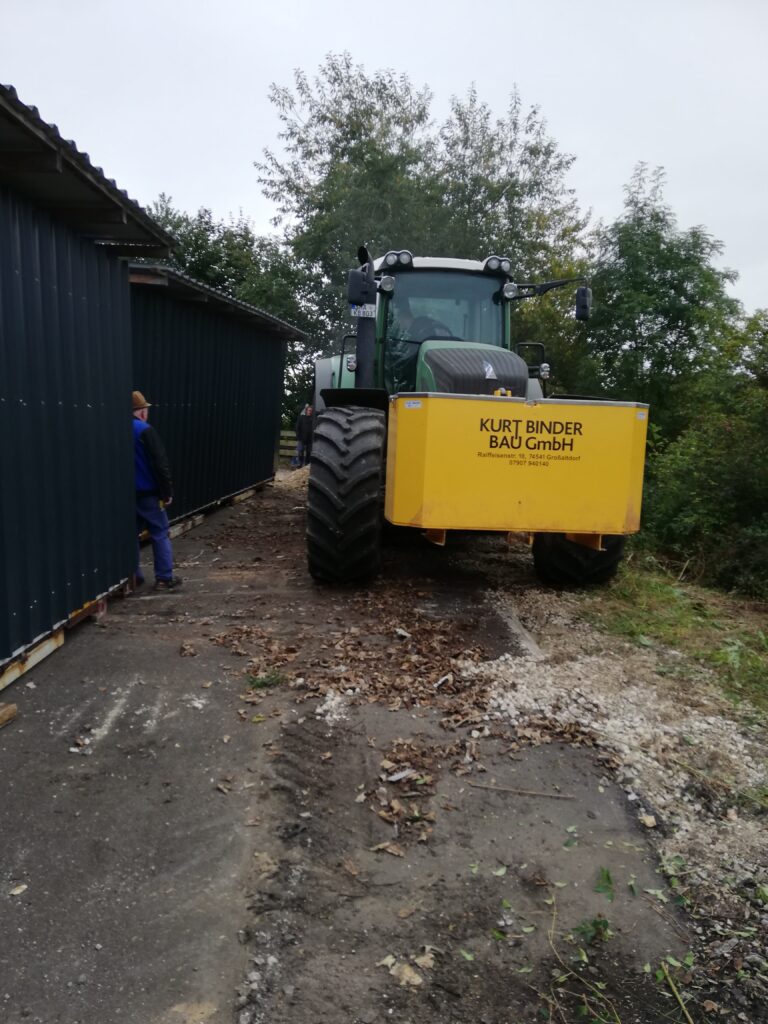 Ein Traktor neben einer Anlage im Außenbereich der Firma Ebert Kunststoffbearbeitung.