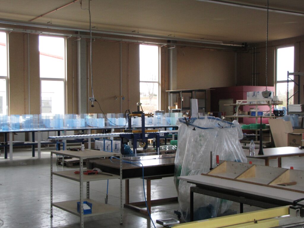 Innenansicht der Halle 3 bei Ebert Kunststoffbearbeitung mit Arbeitsplaetzen und Fenstern